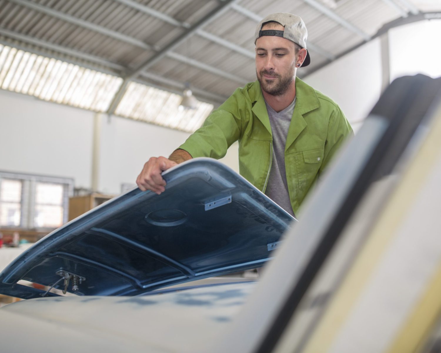 Man fitting car part in bodywork repair shop