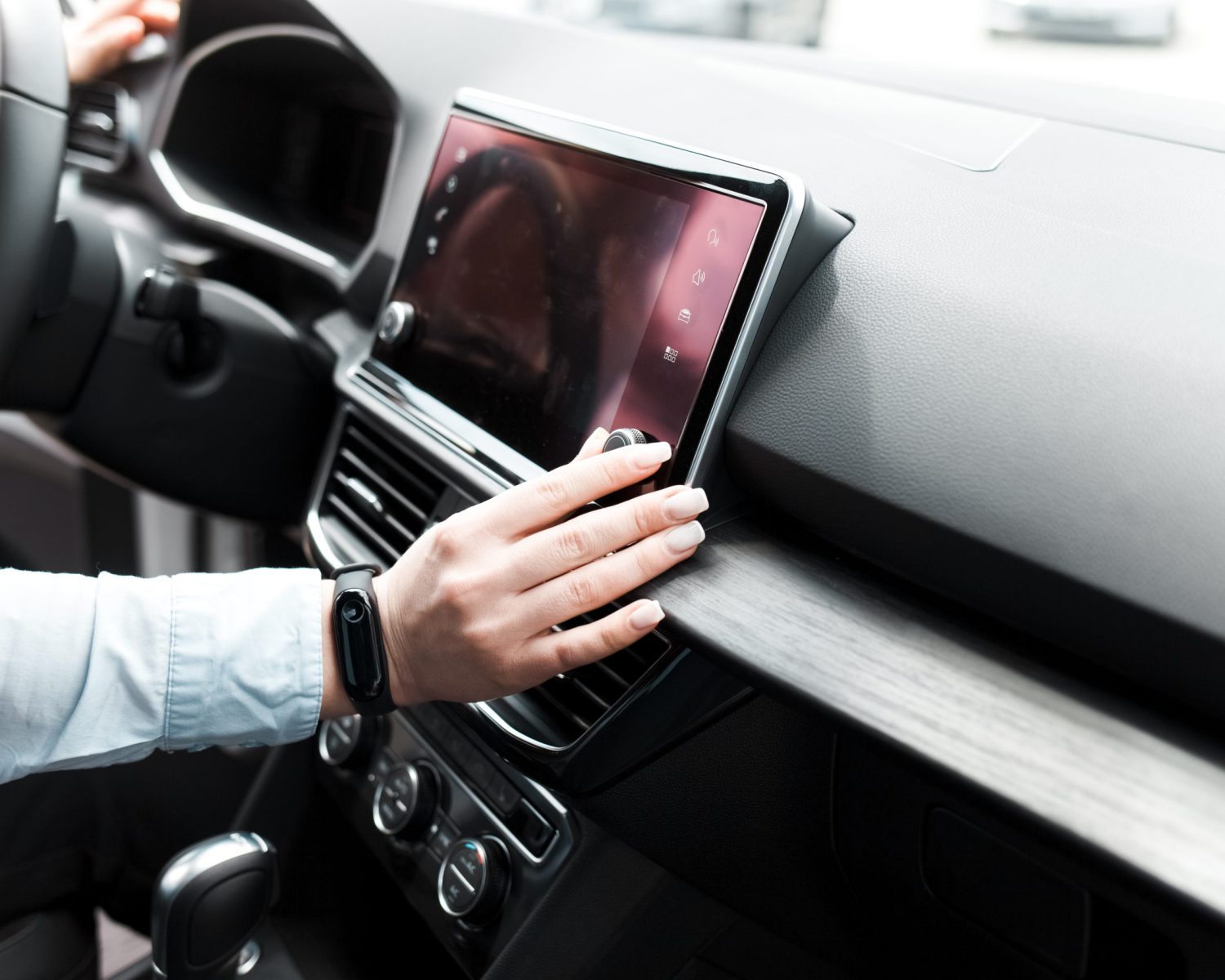 Woman twists the controls on the car radio. Listening to the radio in the car